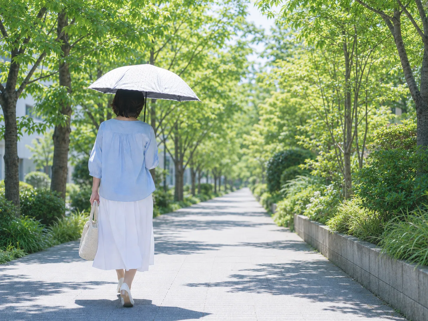 紫外線 夏の日差しの中を日傘で紫外線対策をする50代女性
